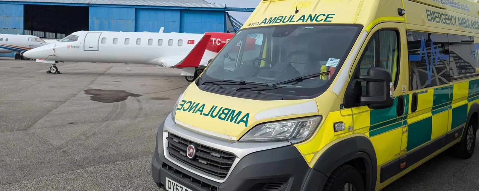 An emergency ambulance on stand beside an air ambulance jet