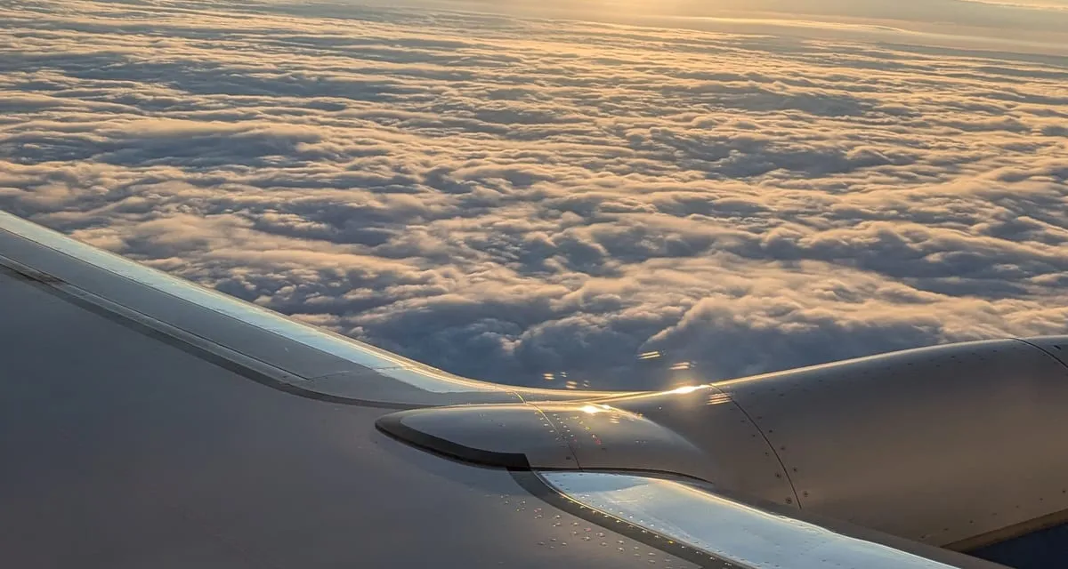 Sunrise over an unbroken cloud layer seen from the cabin of an aircraft at altitude