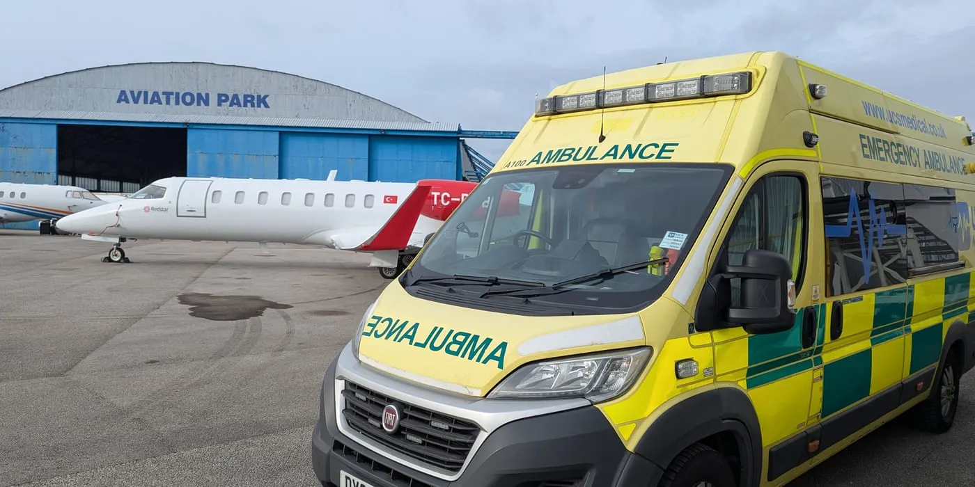 An emergency ambulance on stand beside an air ambulance jet at Aviation Park, ready for a bed-to-bed transfer